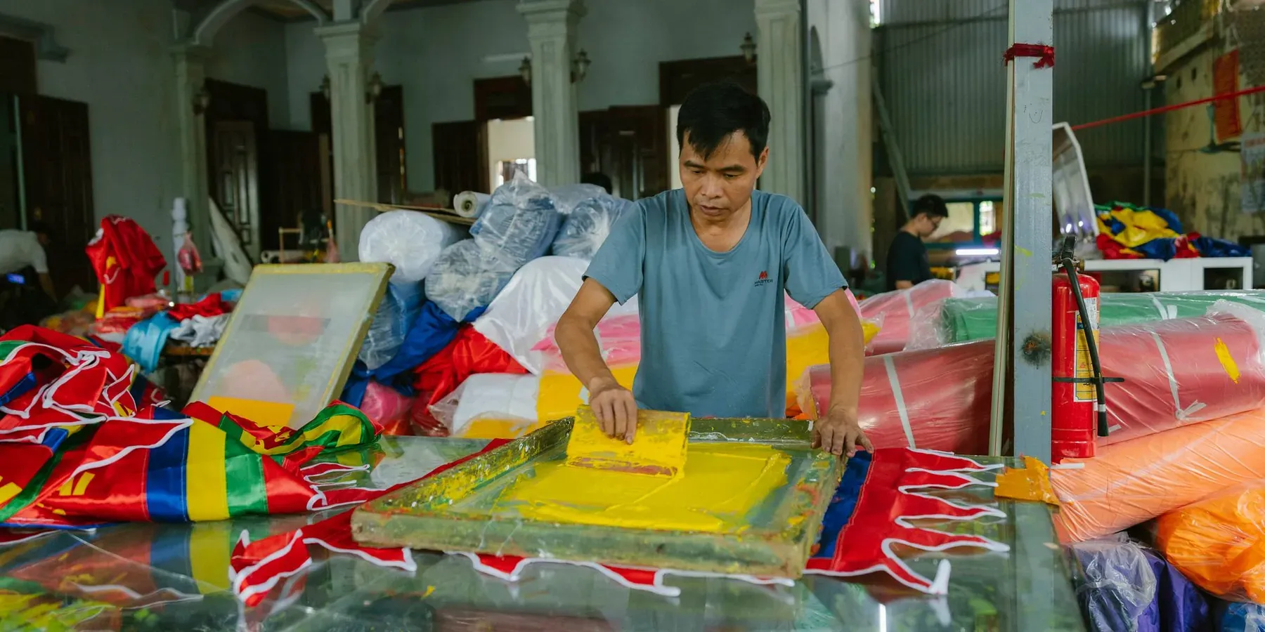 A printer pulling a screen across a shirt in an apparel workshop