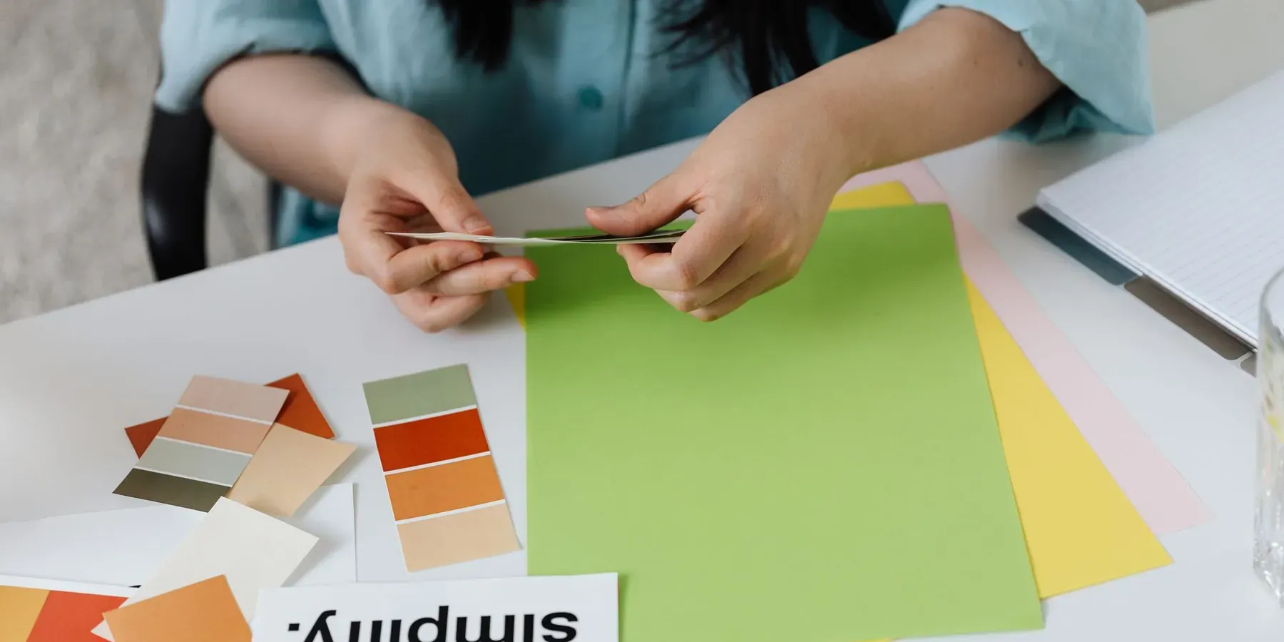 A designer laying out colour swatches and paper samples on a desk