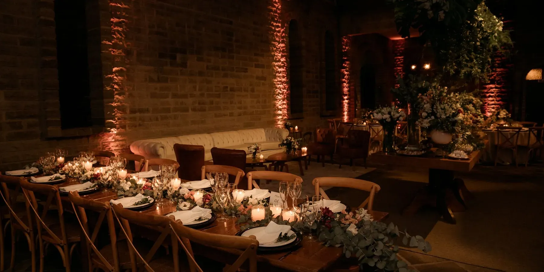 A long banquet table set with candles and flowers in a decorated event hall