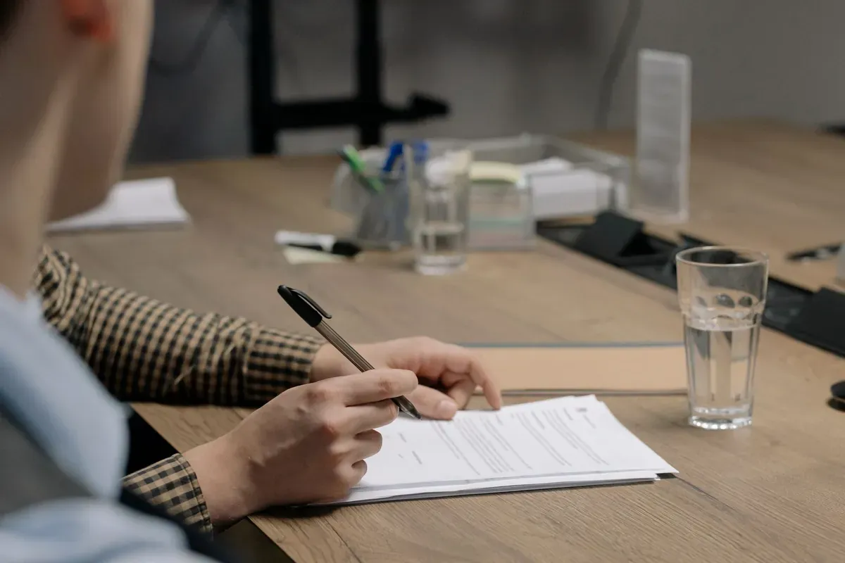 Signing a printed form at a wooden table