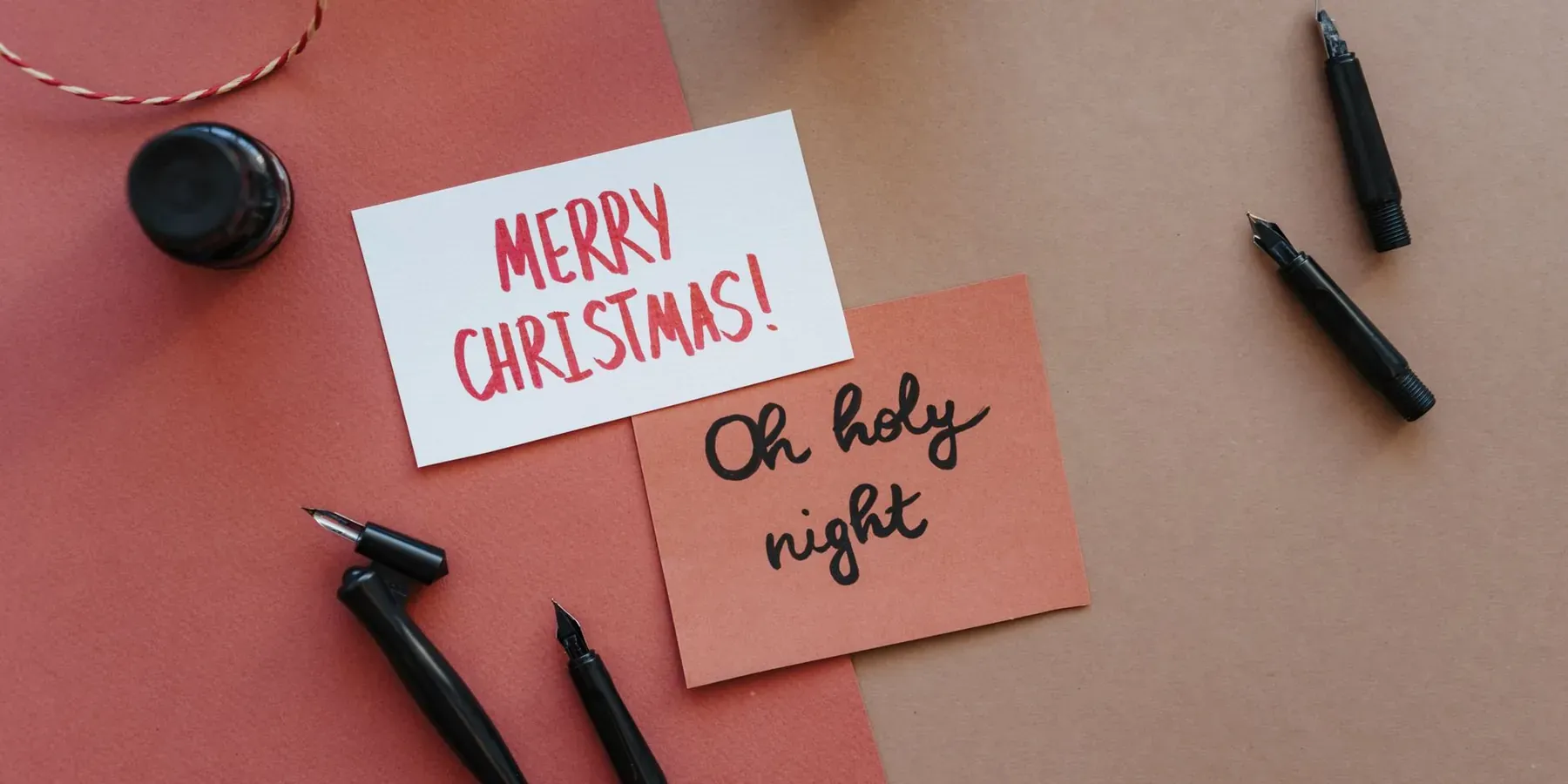 Handwritten holiday cards and calligraphy pens on a desk