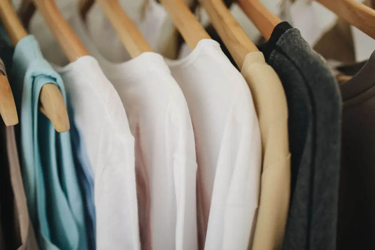 Colorful shirts on wooden hangers on a store rack