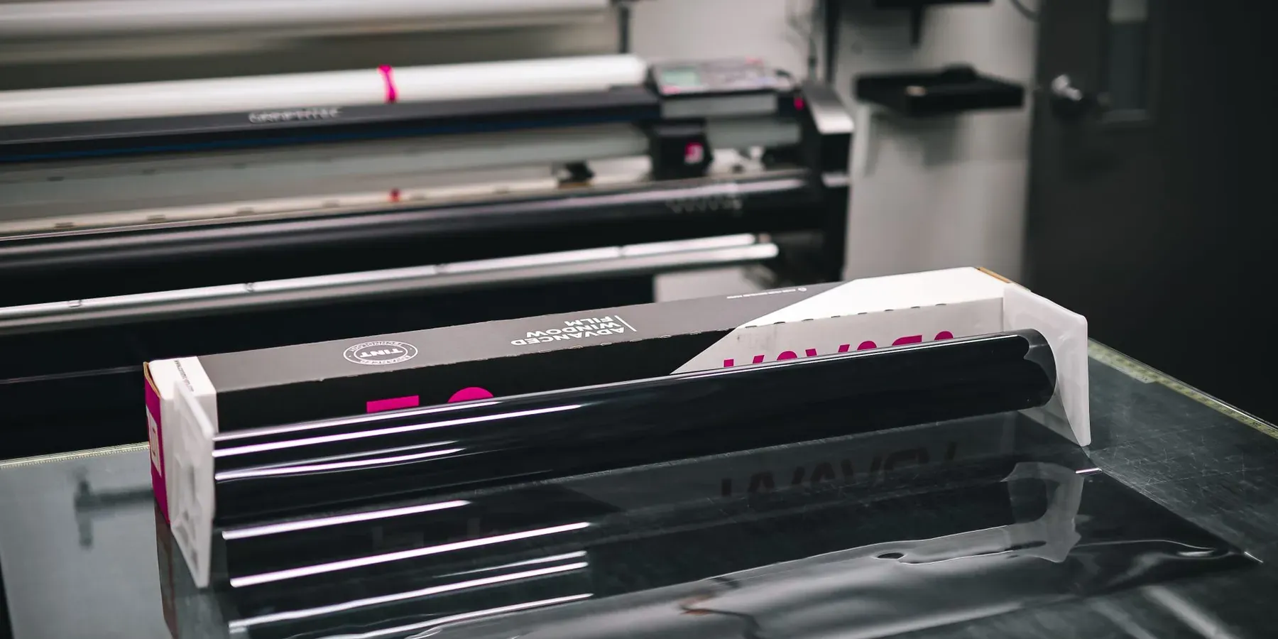 Rolls of sign vinyl loaded in a wide-format cutter at a print shop